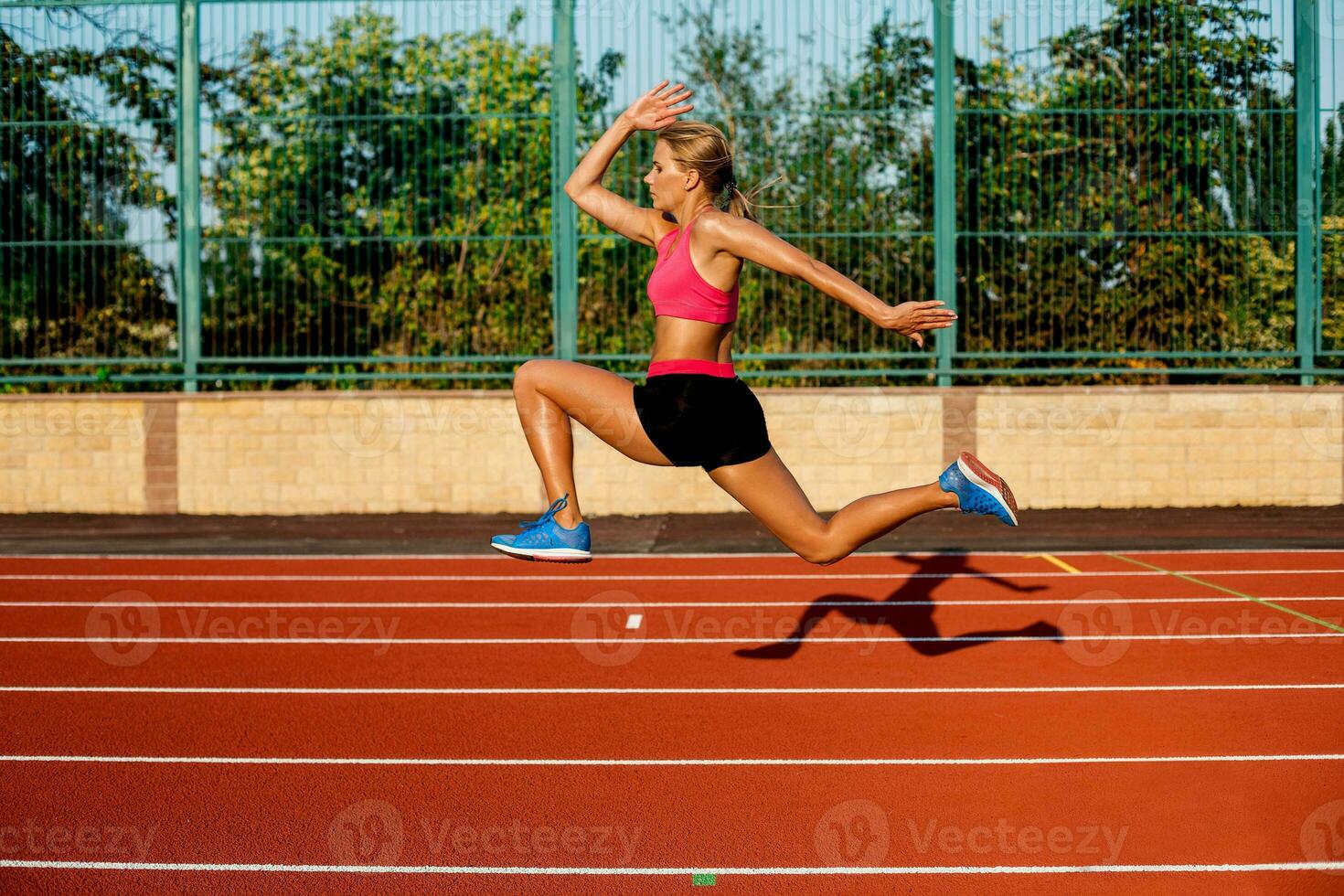 lado Visão lindo jovem mulher exercício corrida e corrida em Atlético rastrear em estádio foto