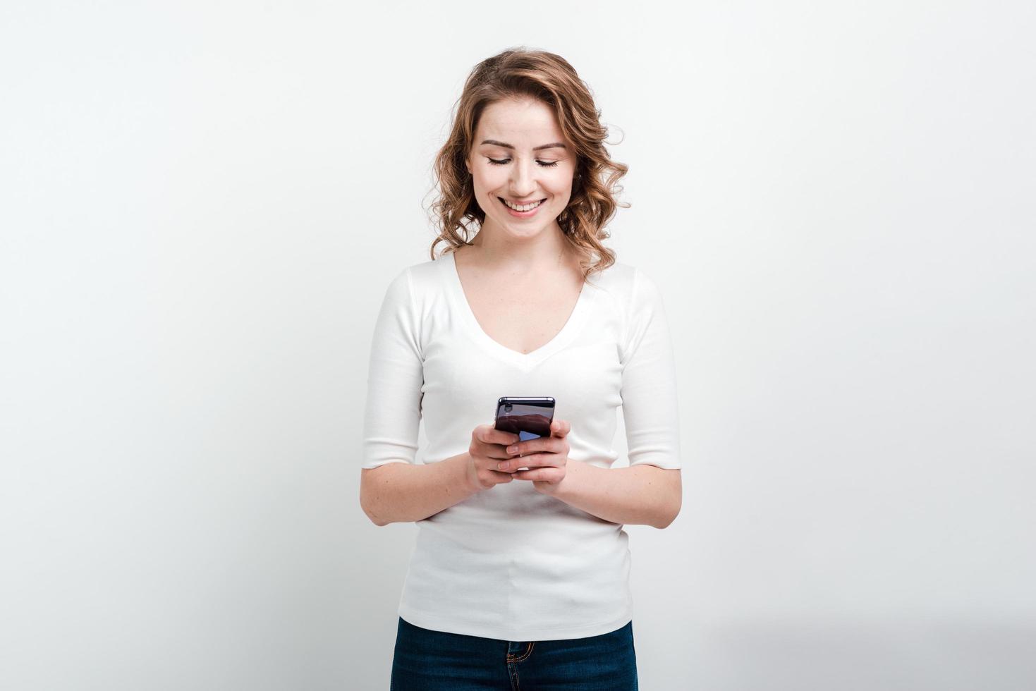garota sorridente segurando um telefone na mão. foto
