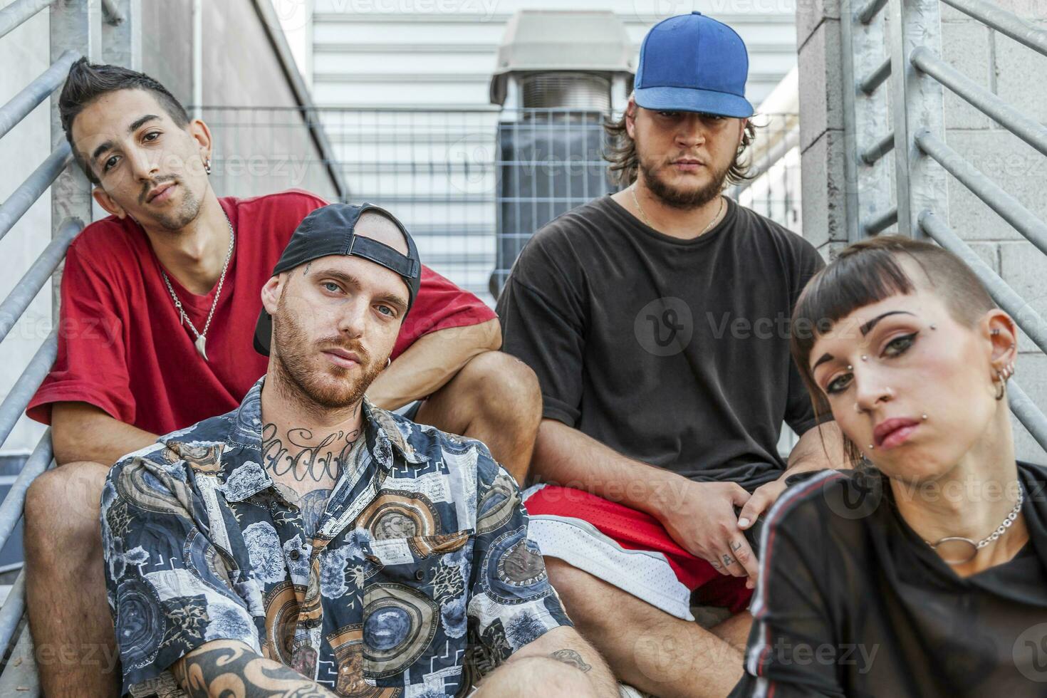 grupo do jovem rappers posando sentado em a metal escadas foto