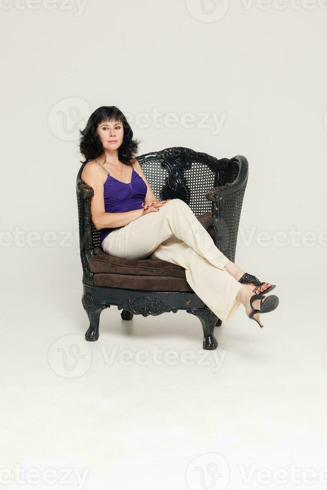 retrato do uma deslumbrante elegante modelo sentado dentro uma cadeira foto