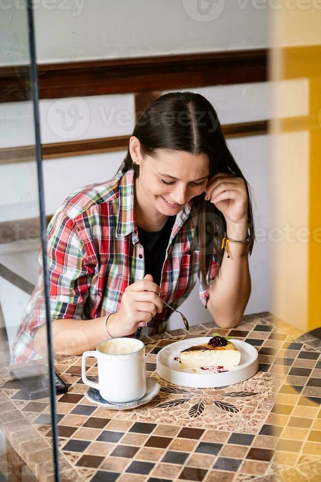 sozinho bonita mulher comendo bolo dentro cafeteria. foto