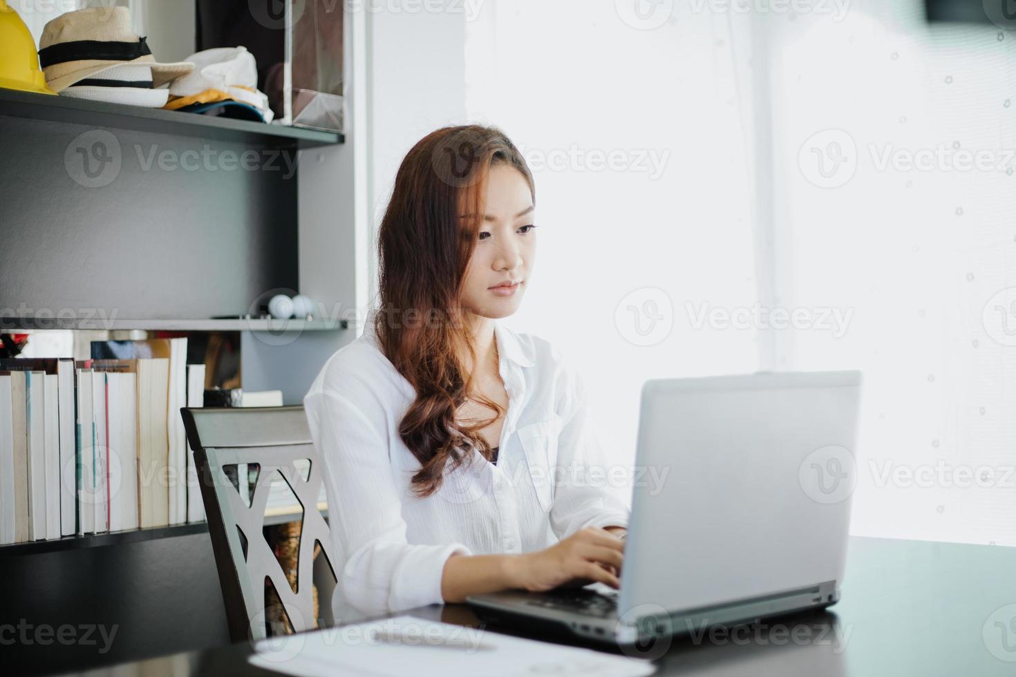 Mulheres de negócios asiáticas usando notebook e sorrindo felizes por trabalhar foto