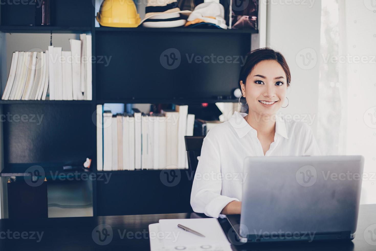 Mulheres de negócios asiáticas usando notebook e sorrindo felizes por trabalhar foto