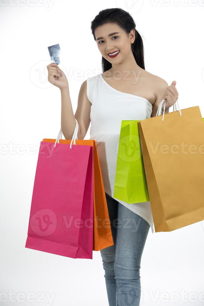 Mulher asiática e linda garota estão segurando sacolas de compras, usando um telefone inteligente e sorrindo enquanto fazem compras e compram com cartão de crédito foto