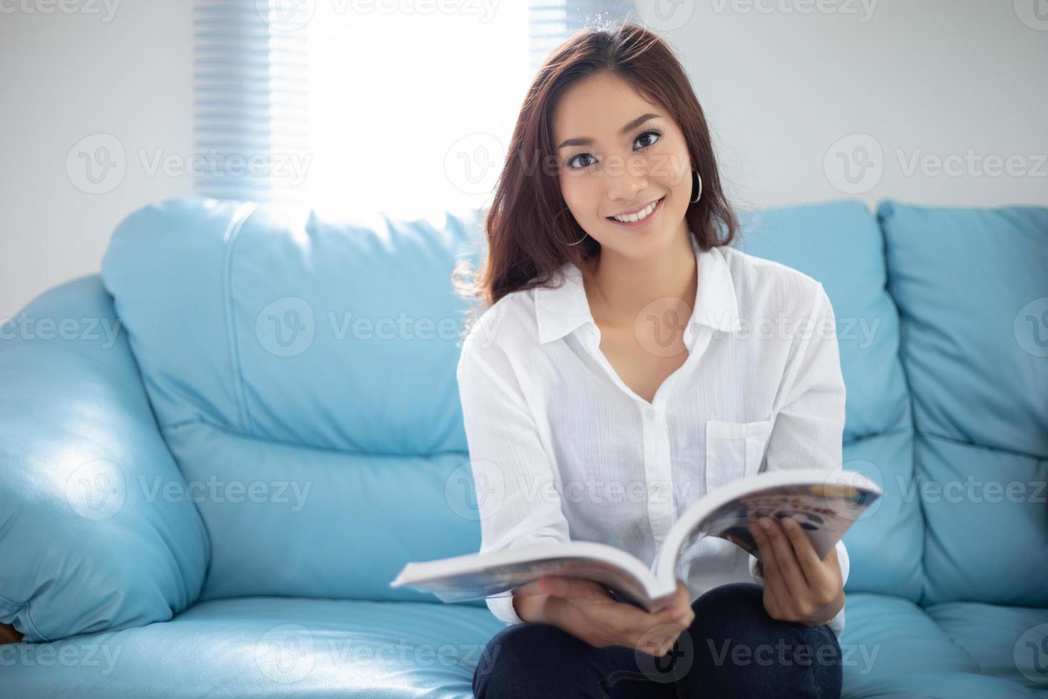 mulheres asiáticas sorrindo e lendo um livro para relaxar em casa foto