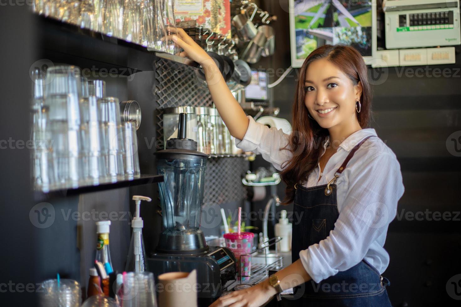 Barista de mulheres asiáticas sorrindo e usando a máquina de café no balcão da cafeteria - conceito de café de comida e bebida de proprietário de uma pequena empresa de trabalho mulher foto