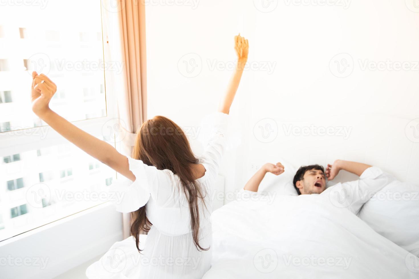 amante de casais acordando em sua cama totalmente descansado e abrir as cortinas pela manhã para tomar ar fresco. foto