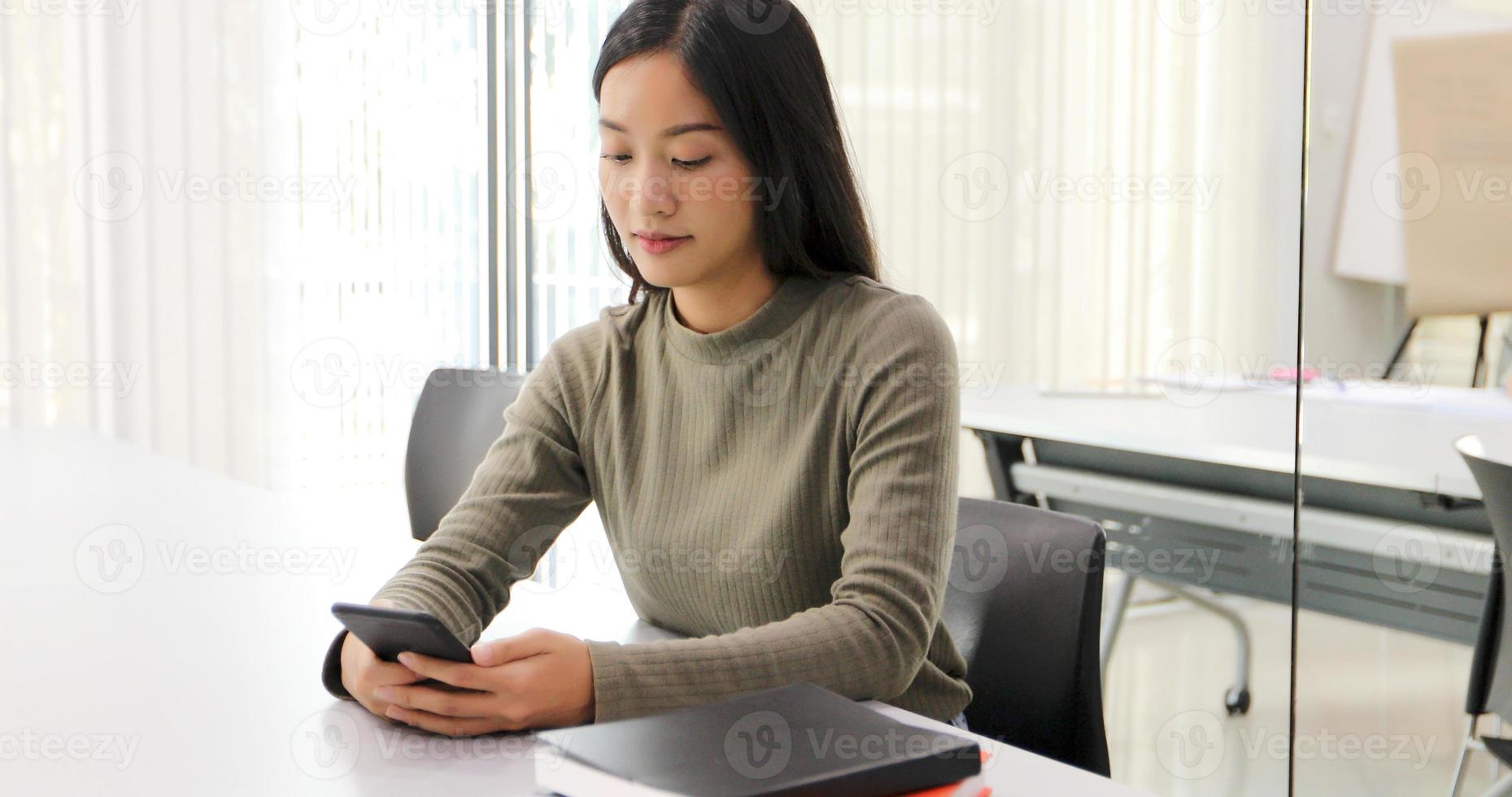 Alunos de mulheres asiáticas sorriem e se divertem e usando smartphone e tablet também ajuda a compartilhar ideias no trabalho e no projeto. foto