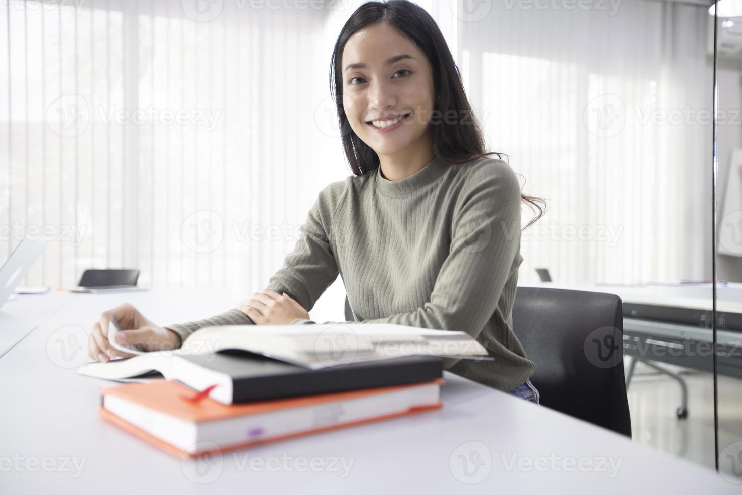 Alunos de mulheres asiáticas sorriem e lendo o livro e usando o caderno para ajuda a compartilhar ideias no trabalho e no projeto. e também revisar o livro antes do exame foto