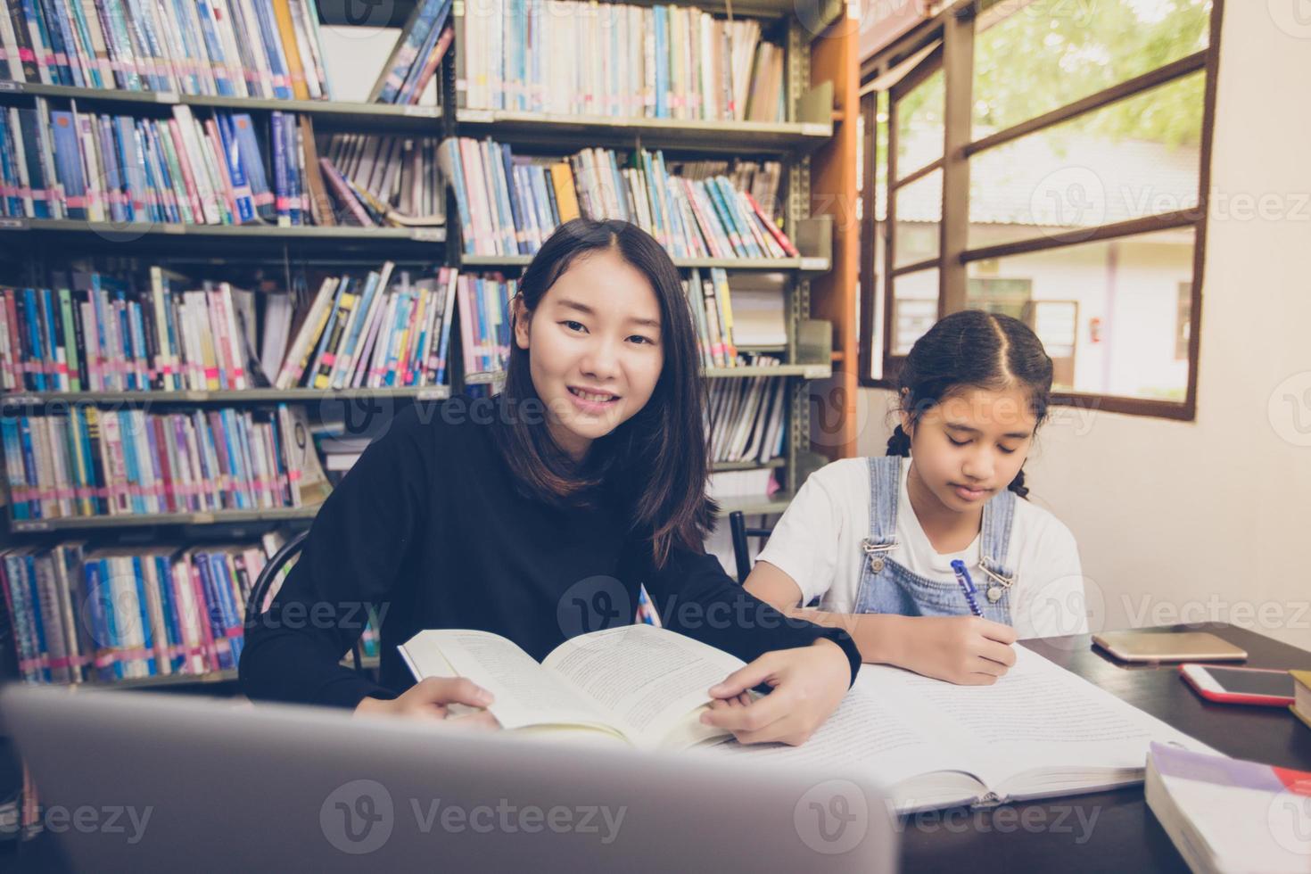estudantes asiáticos lendo livros na biblioteca. foto