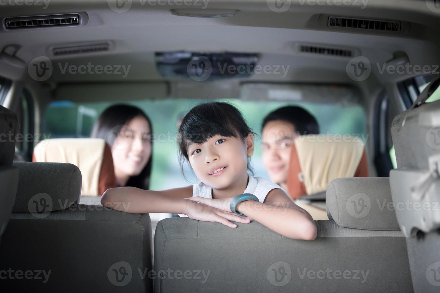 menina feliz com uma família asiática sentada no carro para aproveitar a viagem e as férias de verão em uma van de camping foto