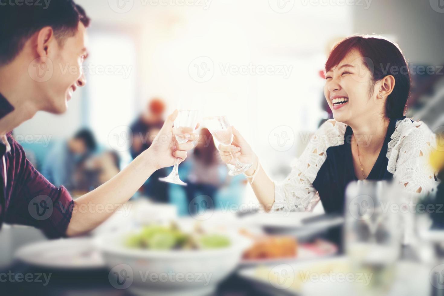 jovem casal asiático desfrutando de um jantar romântico drinques enquanto está sentado à mesa de jantar na cozinha juntos em casa, foco suave foto