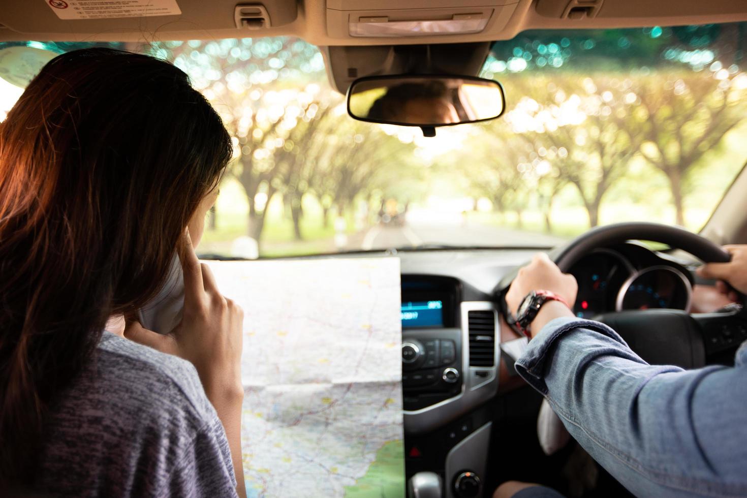 homem asiático e mulher usando celular na viagem e casal jovem feliz com um mapa no carro. foco turvo e suave foto