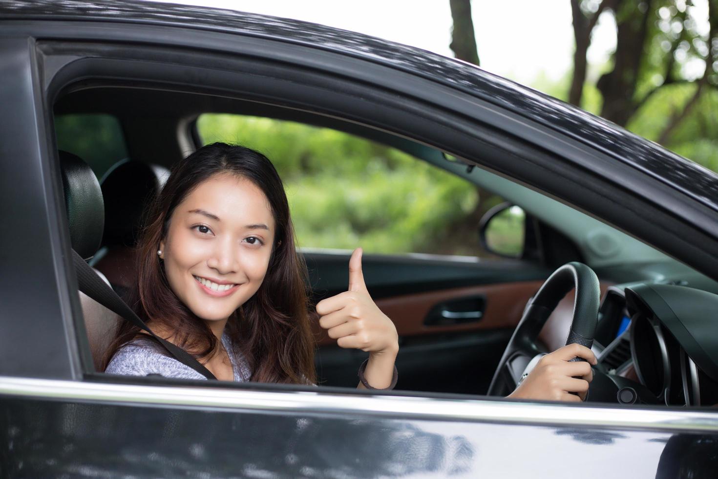 linda mulher asiática sorrindo e se divertindo. dirigindo um carro na estrada para viajar foto