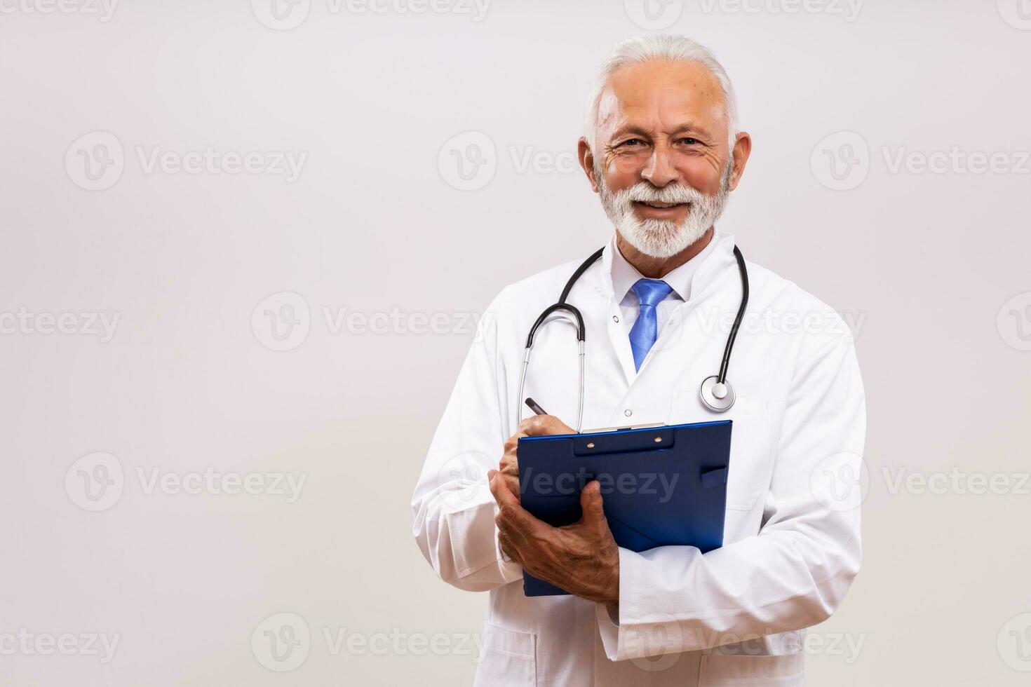 retrato do Senior médico escrevendo notas em cinzento fundo. foto