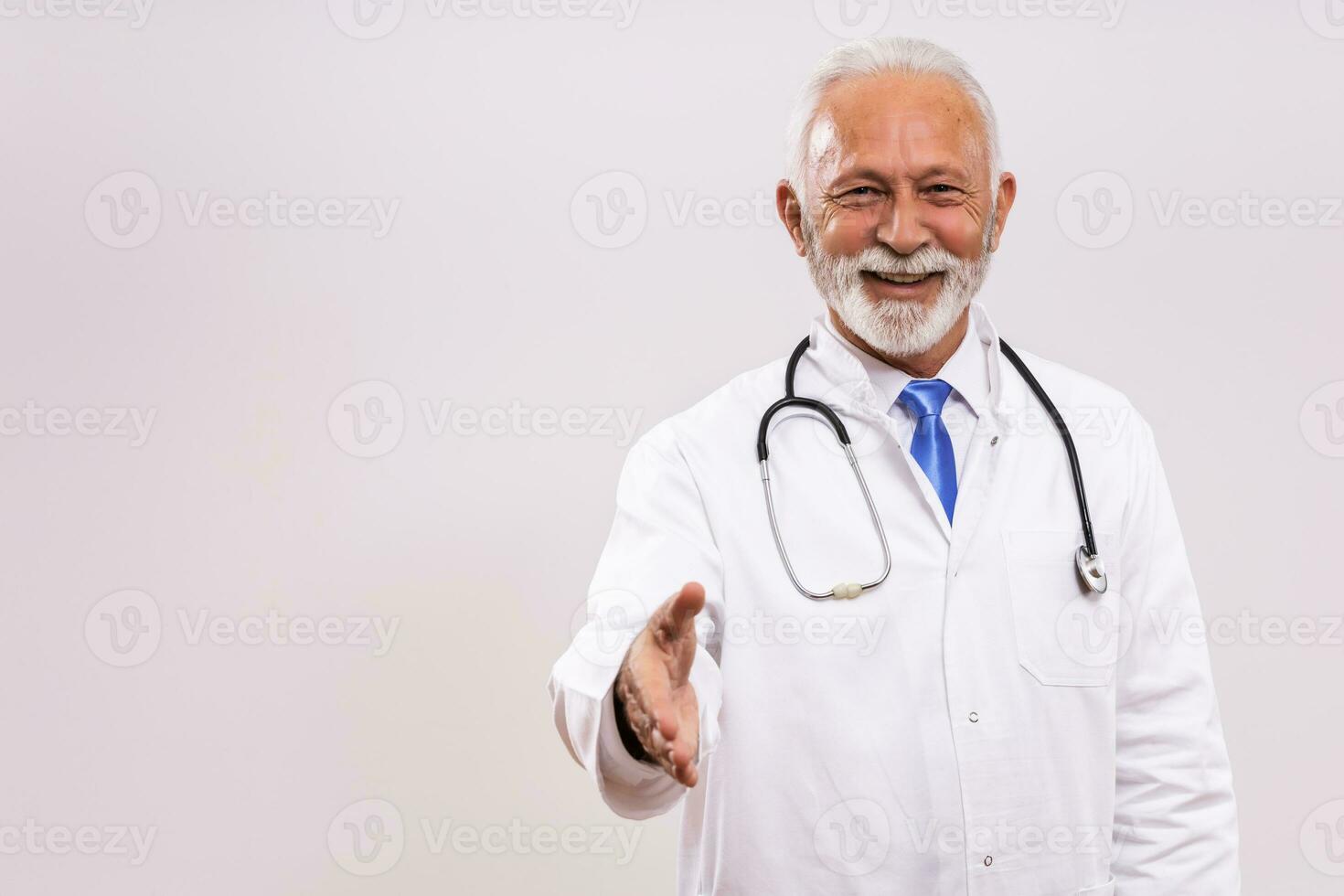 Senior médico mostrando aperto de mão gesto em cinzento fundo. foto