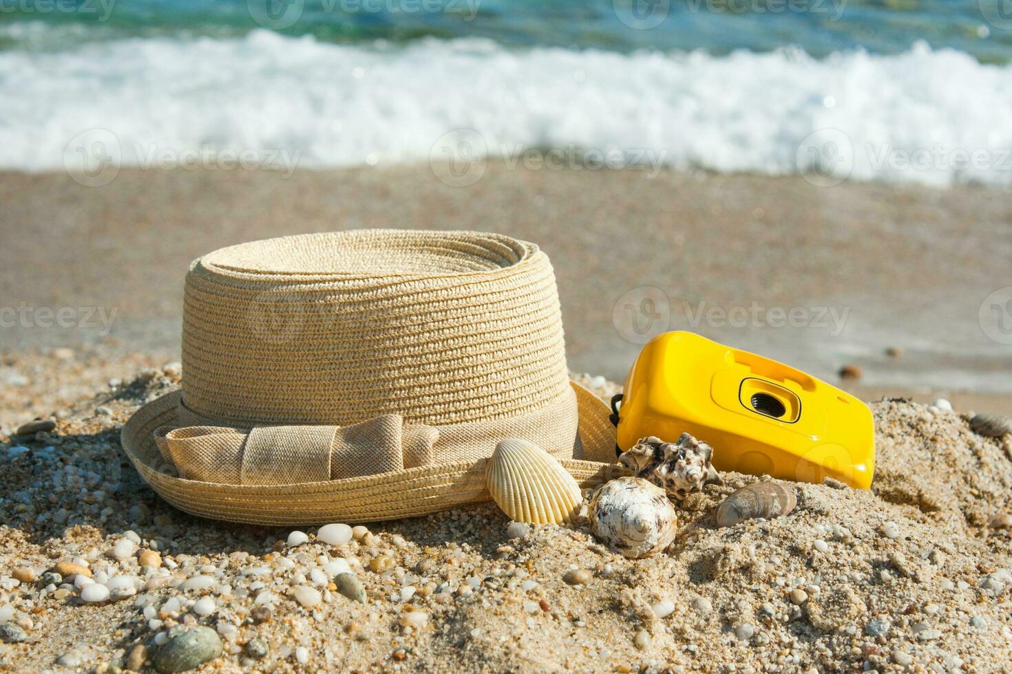 chapéu e Câmera em a de praia com uma fundo mar ondas foto