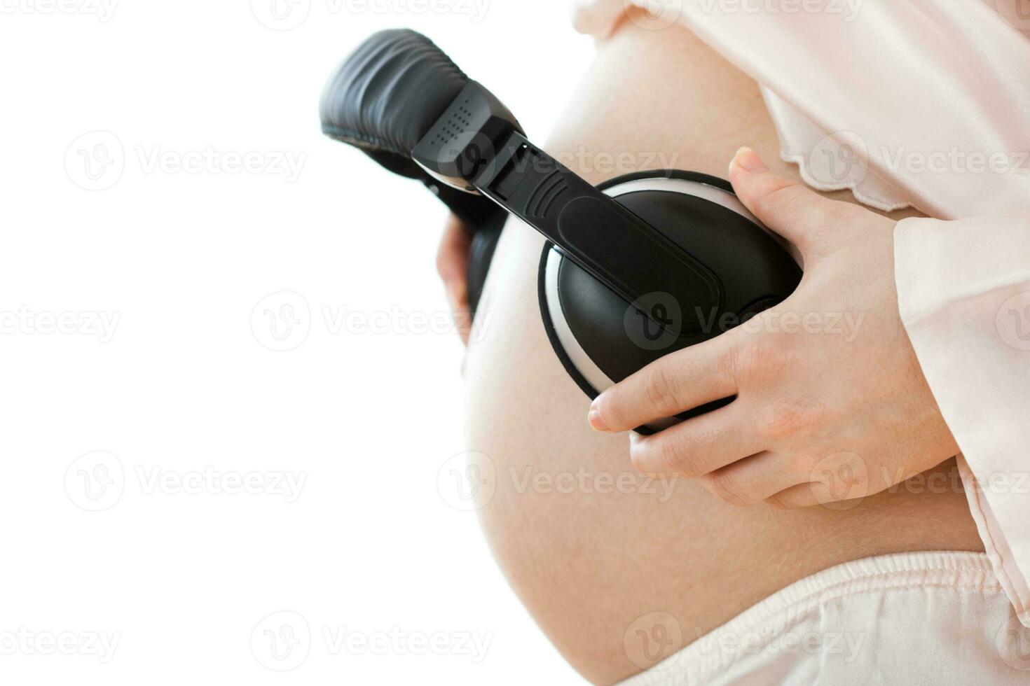 fones de ouvido em uma grávida mulher barriga. foto