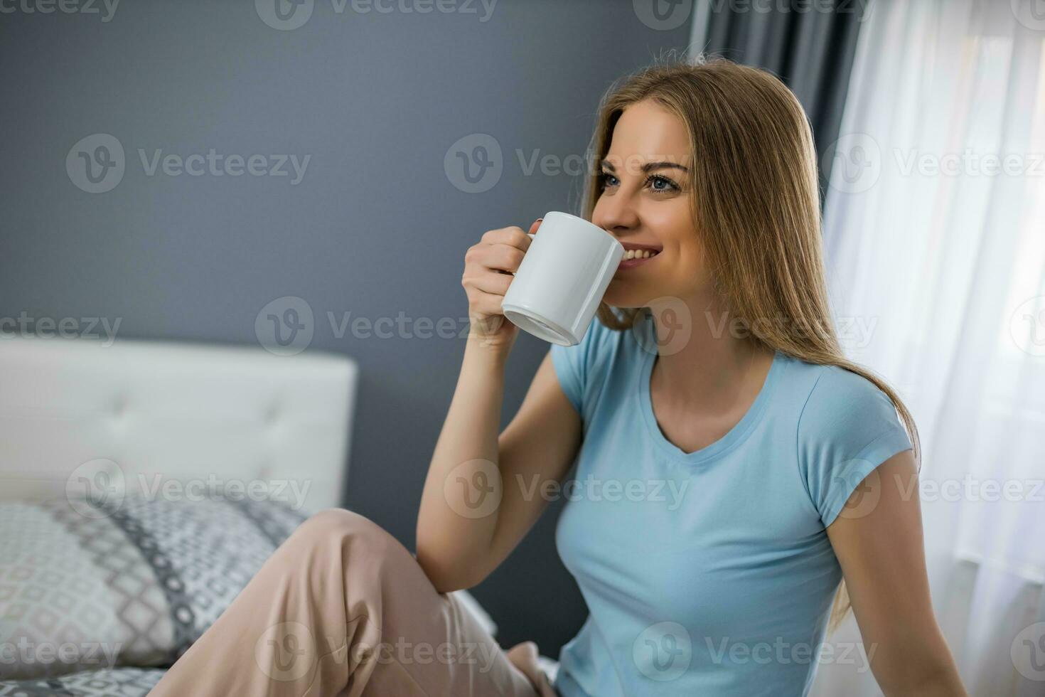 lindo mulher goza bebendo café dentro dela cama. foto