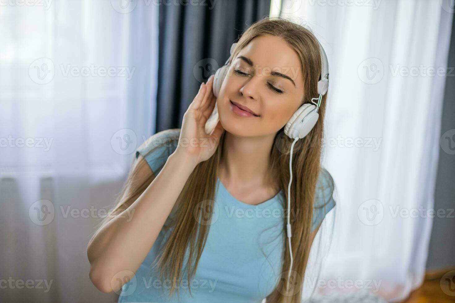 lindo mulher com fones de ouvido goza ouvindo música às lar. foto
