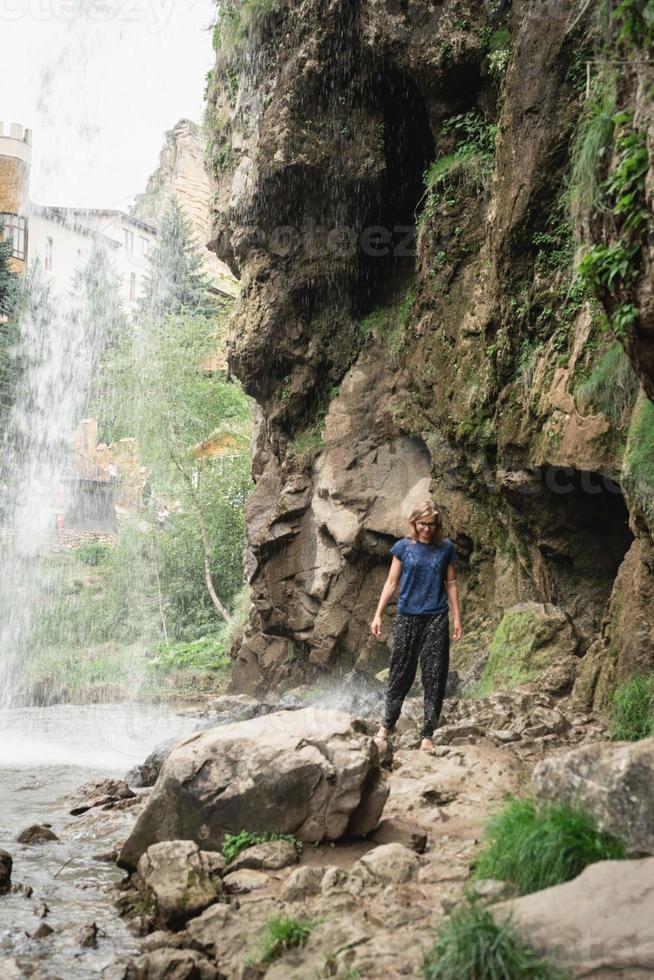 mulher caminhando pela bela cachoeira da montanha foto