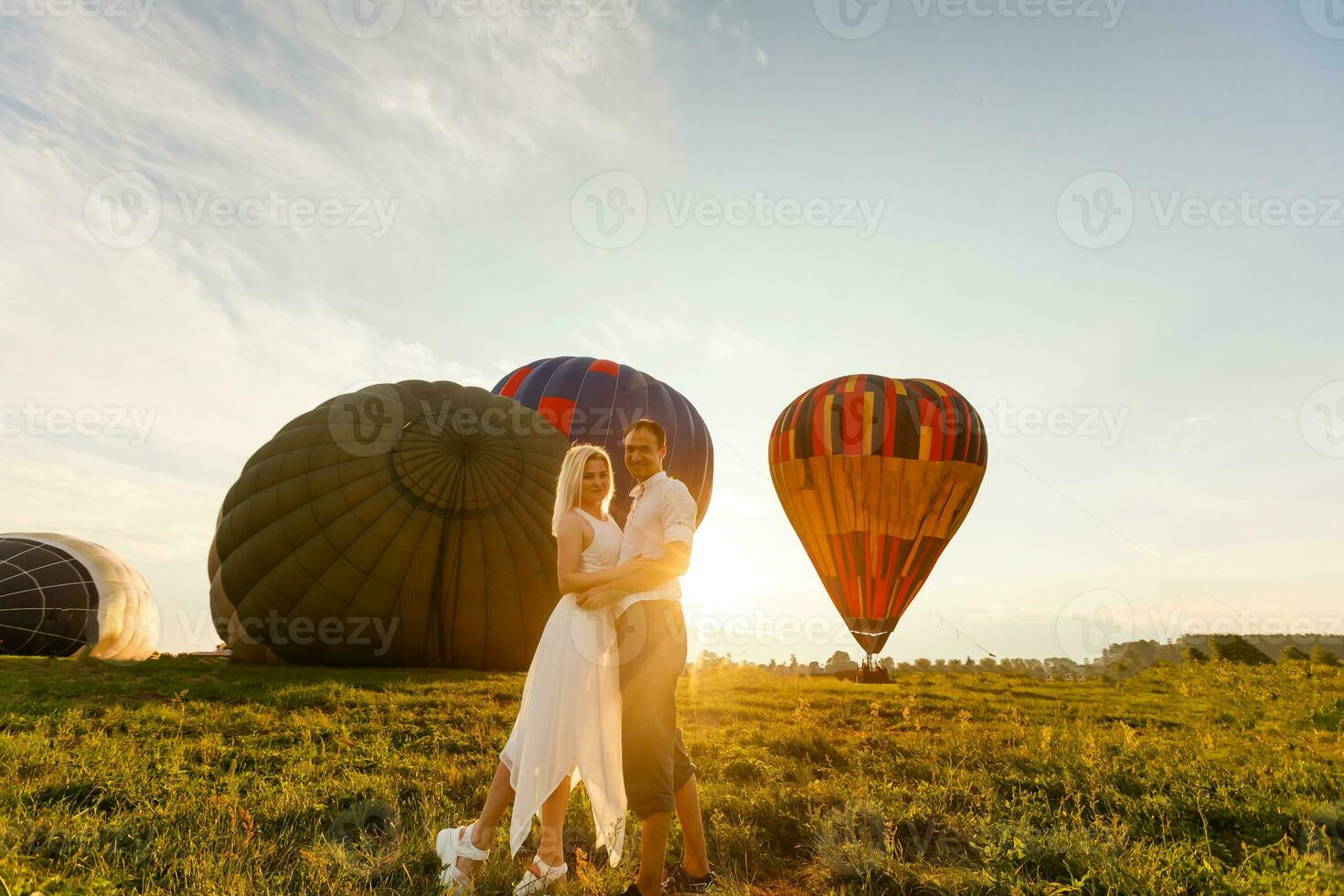 lindo romântico casal abraçando às Prado. quente ar balão em uma fundo foto