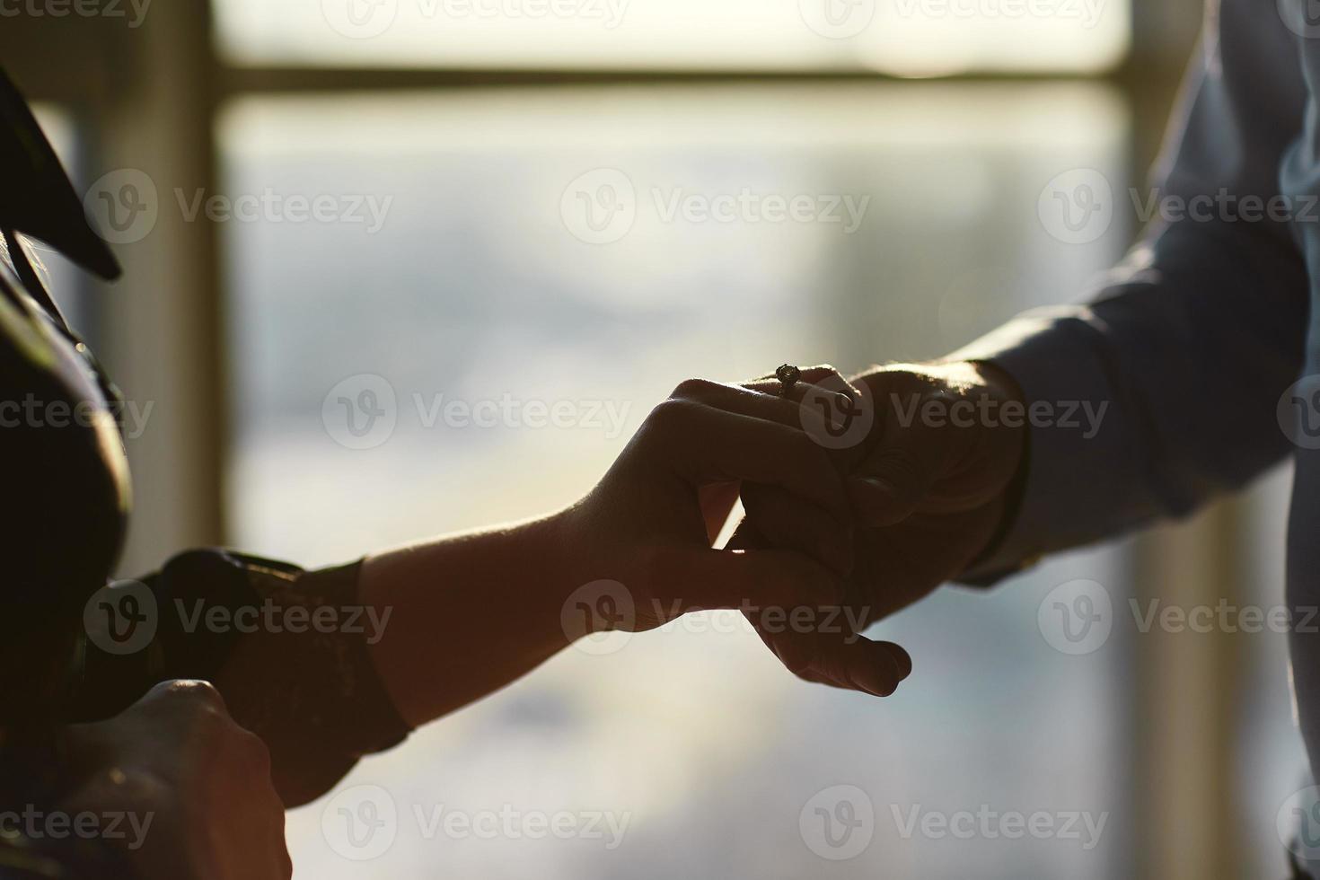 mãos de um jovem casal com um anel. conceito de amor, casal, relacionamento e férias - close-up do homem dando um anel de diamante para a mulher foto