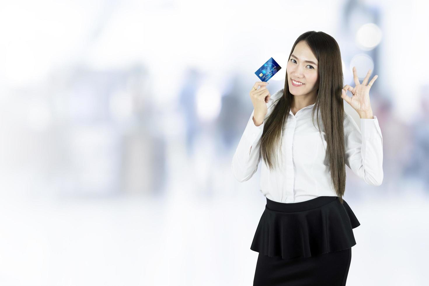 Mulher de negócios asiática mostrando cartão de crédito no fundo desfocado foto