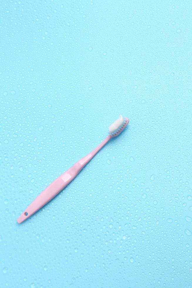 escova de dentes rosa e água sobre fundo azul com um espaço em branco para um texto foto