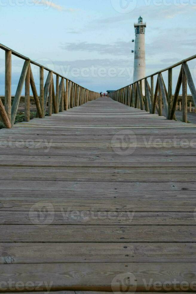 uma de madeira ponte conduz para uma farol foto