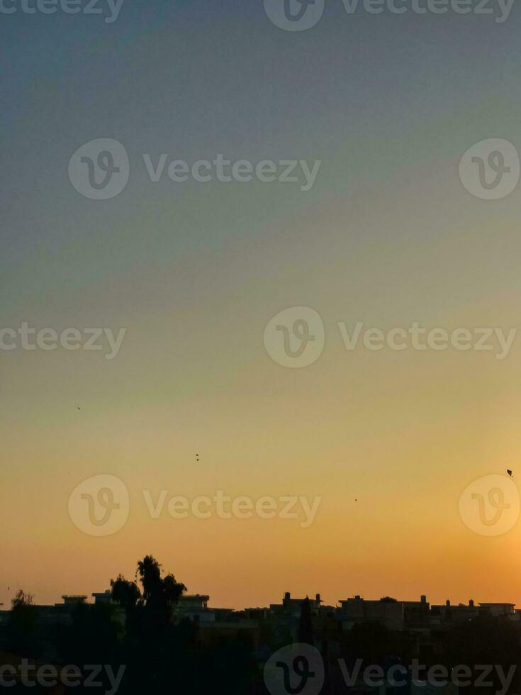 uma pôr do sol sobre uma cidade com pássaros vôo dentro a céu foto