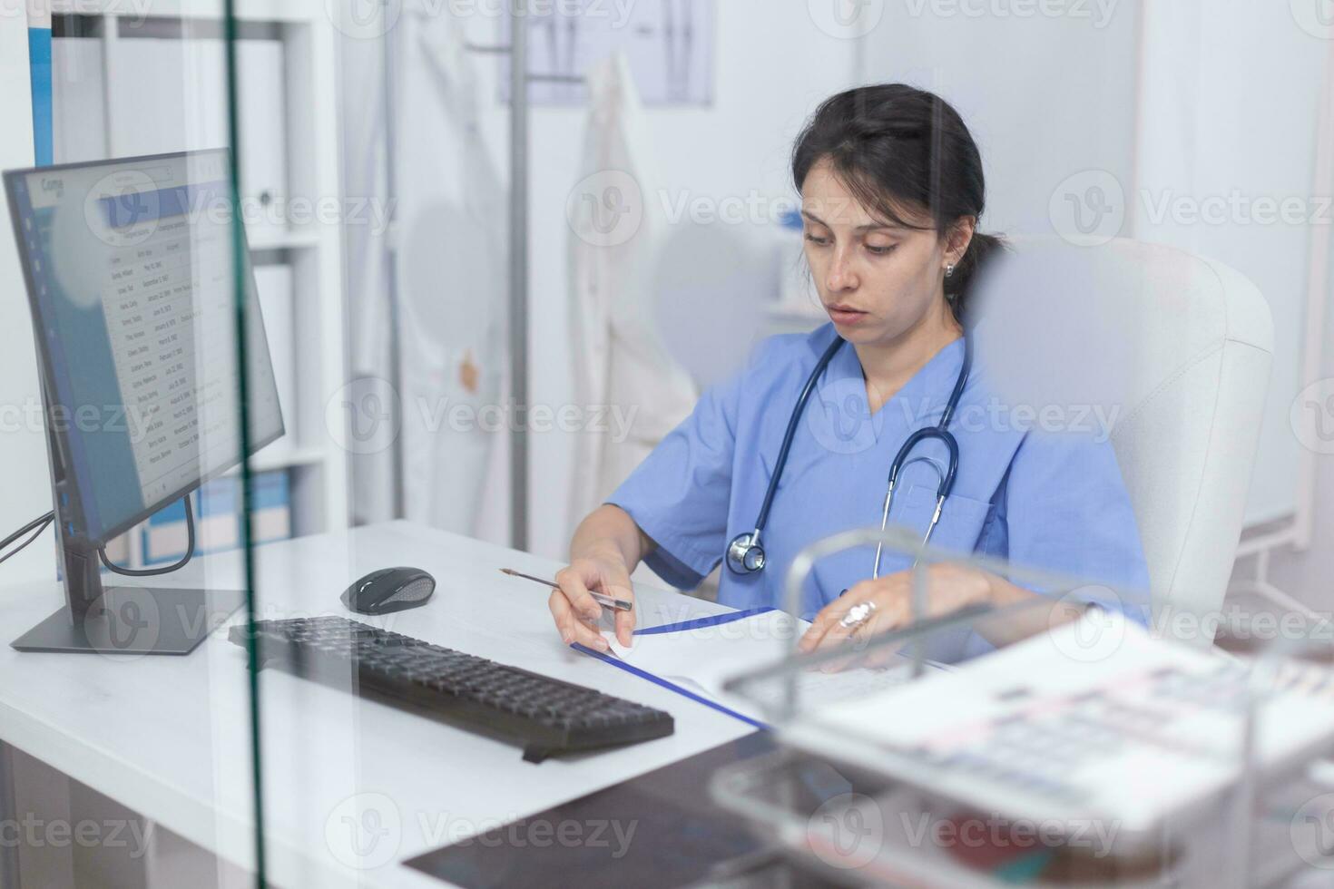 médico funcionários escrevendo notas em prancheta sentado às escrivaninha dentro hospital escritório. cuidados de saúde médico especialista dentro remédio fornecendo saúde Cuidado Serviços tratamento exame. foto