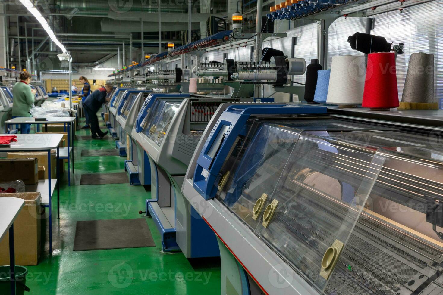 uma linha do industrial textil plano tricô máquinas dentro uma malhas fábrica. foto