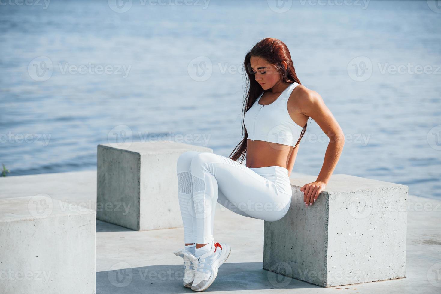 foto de mulher esportiva fazendo exercícios de fitness perto do lago durante o dia