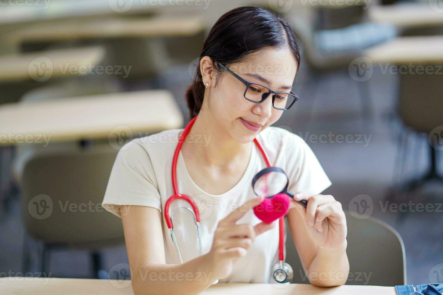 médico aluna segurando uma ampliação vidro e parece às uma fio vermelho coração em borrado fundo. ásia médico aluna com coração doença conceito. foto