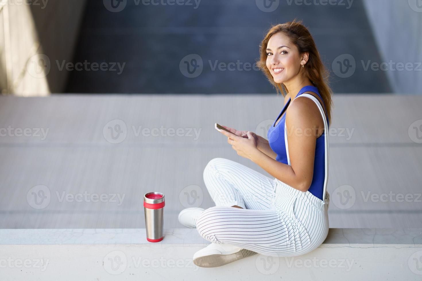 garota usando um smartphone touchscreen com roupas casuais foto