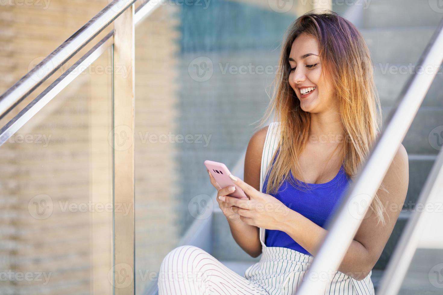 garota usando um smartphone touchscreen com roupas casuais foto