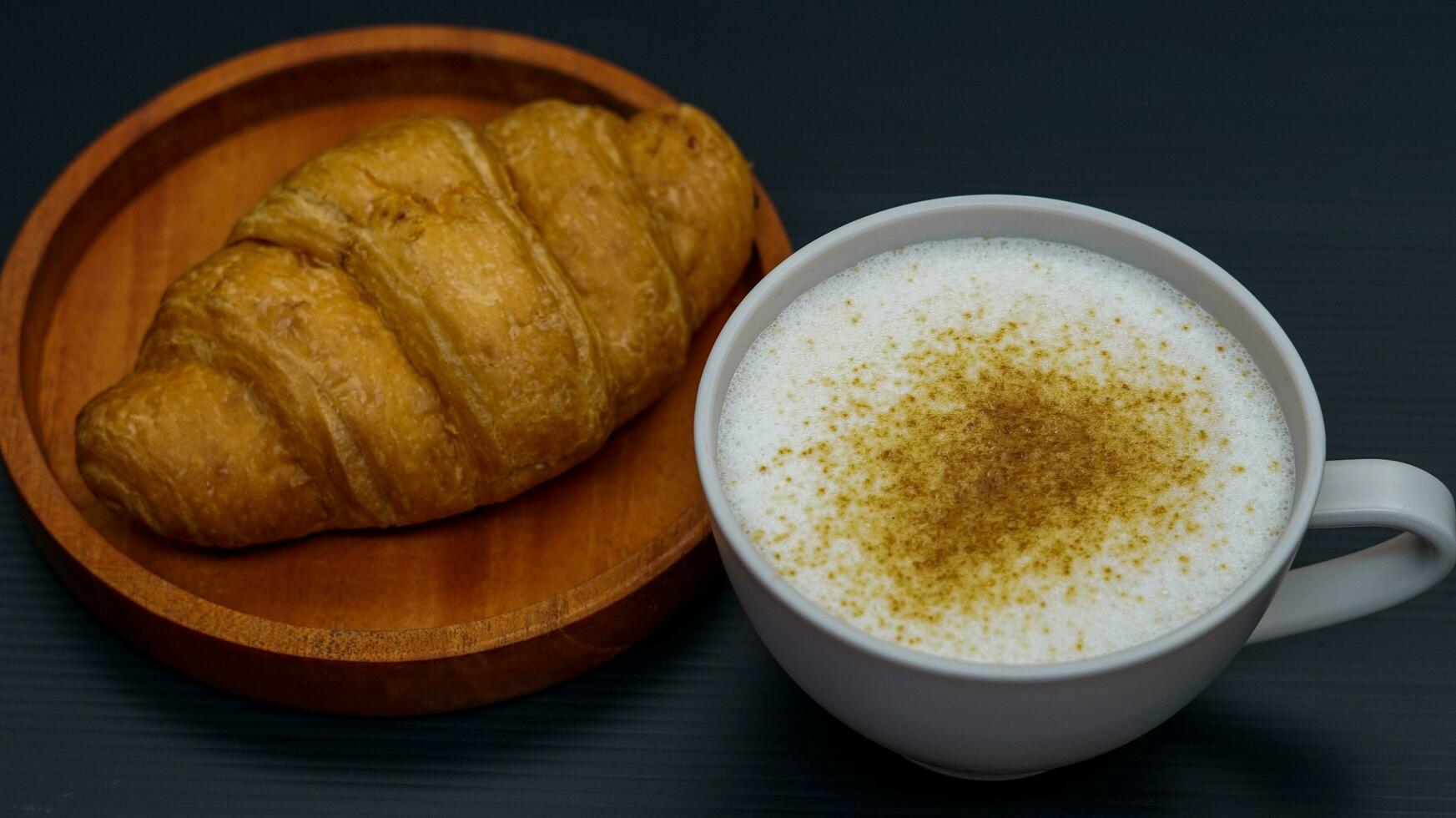 croissant coberto com querida com uma vidro do café café com leite foto