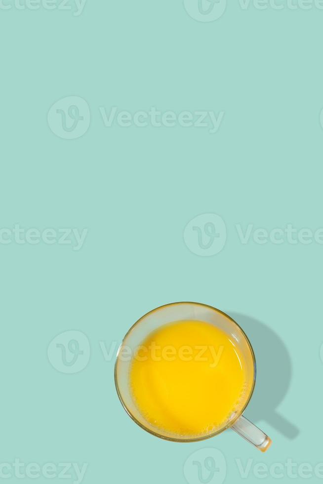 capa com um copo cheio de suco de laranja feito apenas de frutas frescas, com fundo turquesa sólido com espaço de cópia. conceito de alimentação saudável, vitaminas e vida saudável. foto