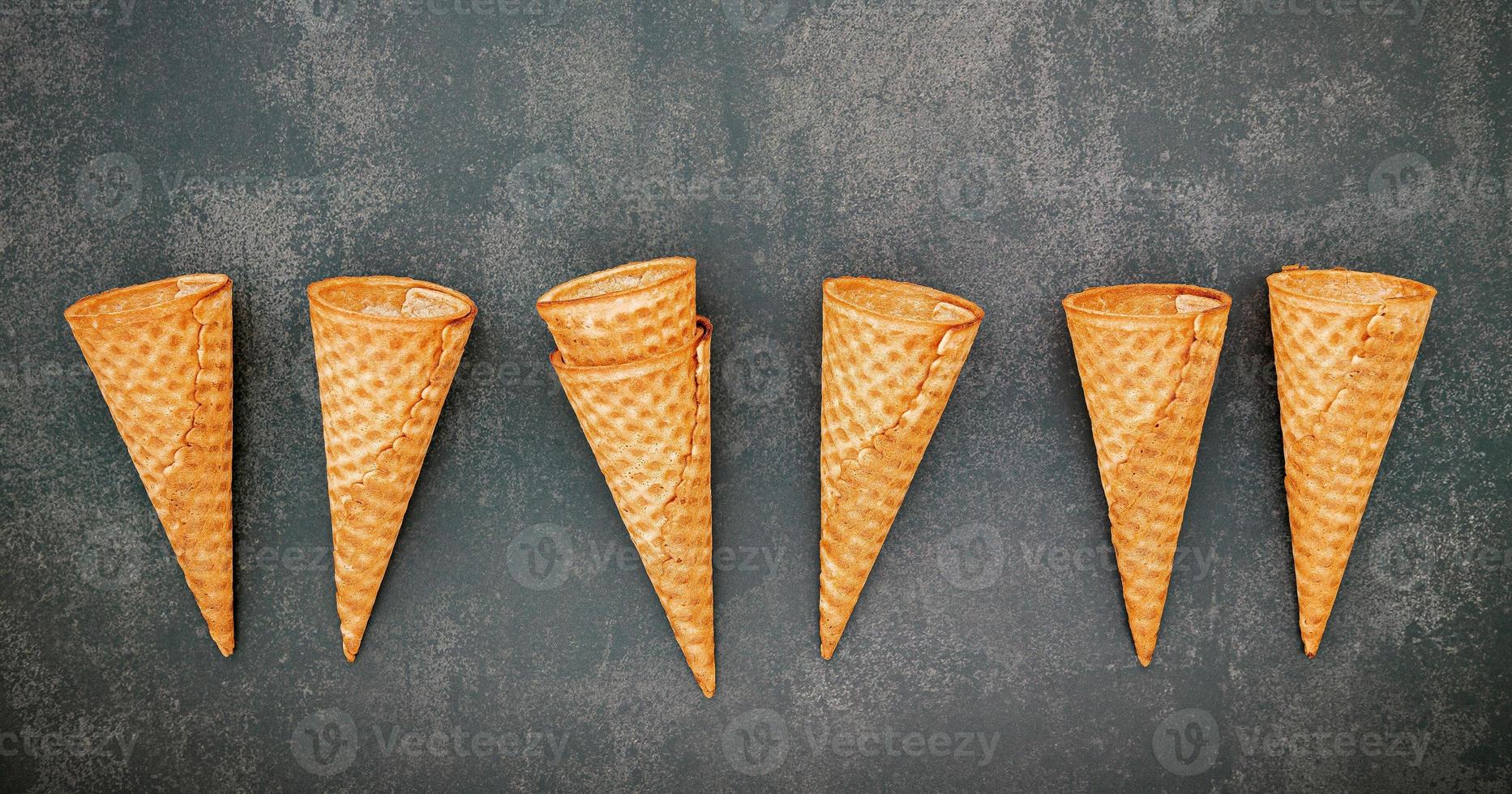 plana leigos coleção de cones de sorvete em fundo de pedra escura. em branco casquinha de sorvete crocante com espaço de cópia para o design do menu de doces. foto