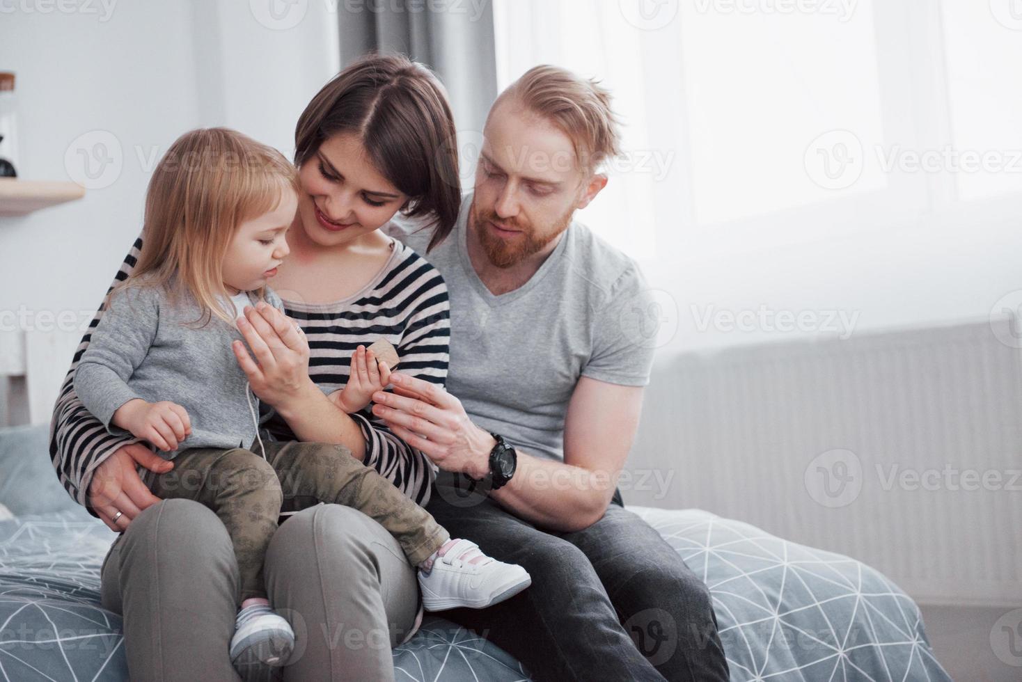 família feliz mãe, pai e filha rindo na cama foto