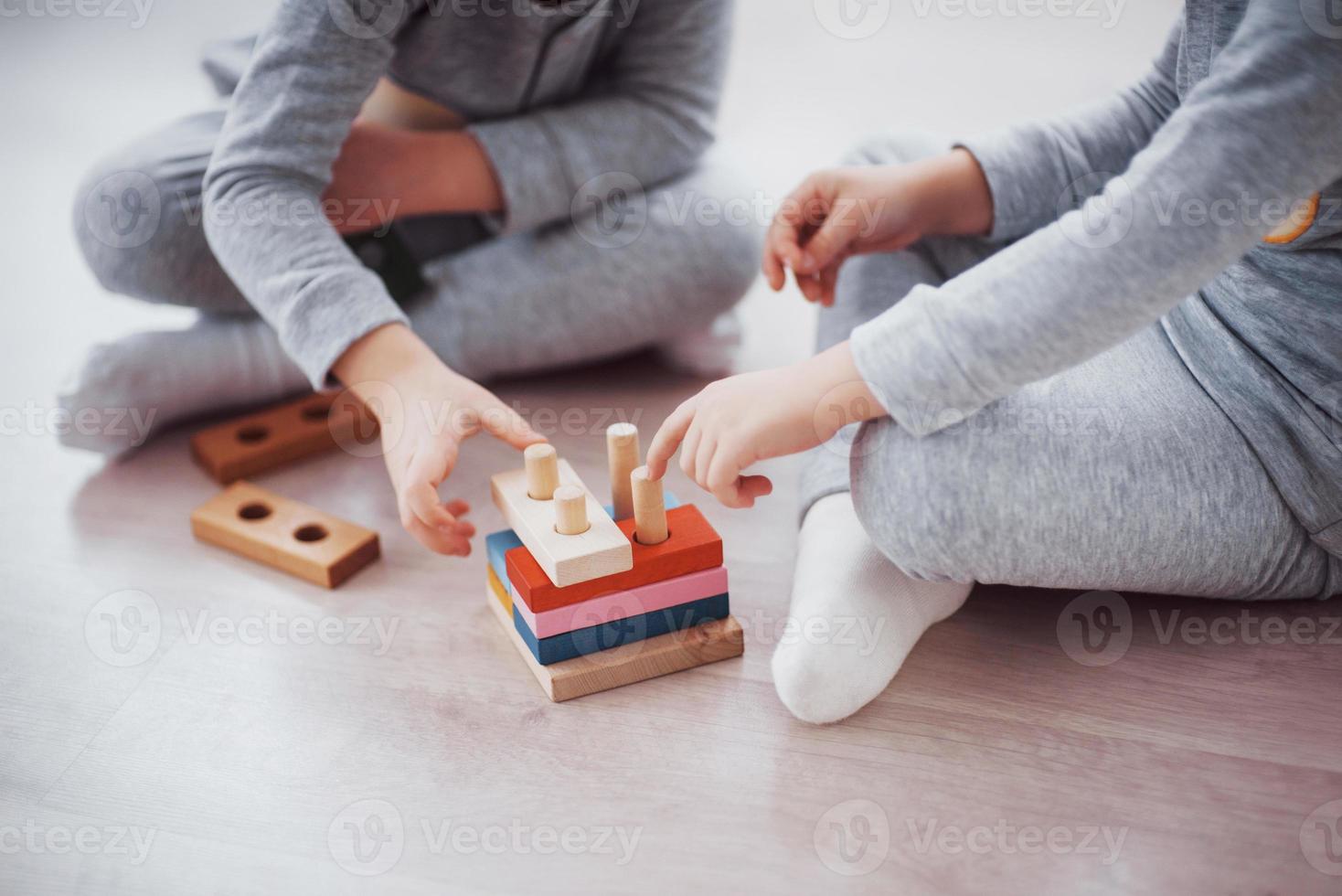 as crianças brincam com um designer de brinquedos no chão do quarto das crianças. duas crianças brincando com blocos coloridos. jogos educativos de jardim de infância foto