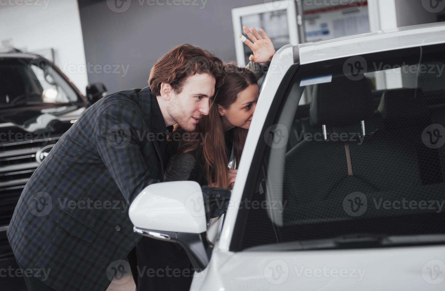 é o único carro que eu quero. lindo casal jovem parado na concessionária escolhendo o carro para comprar foto