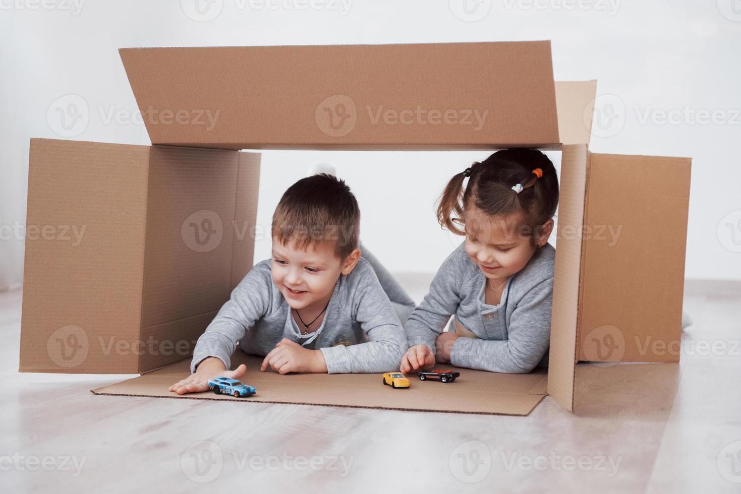 irmãozinho e irmãzinha brincando em caixas de papelão no berçário foto