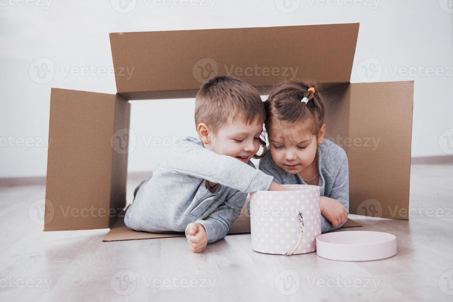 irmãozinho e irmãzinha brincando em caixas de papelão no berçário foto