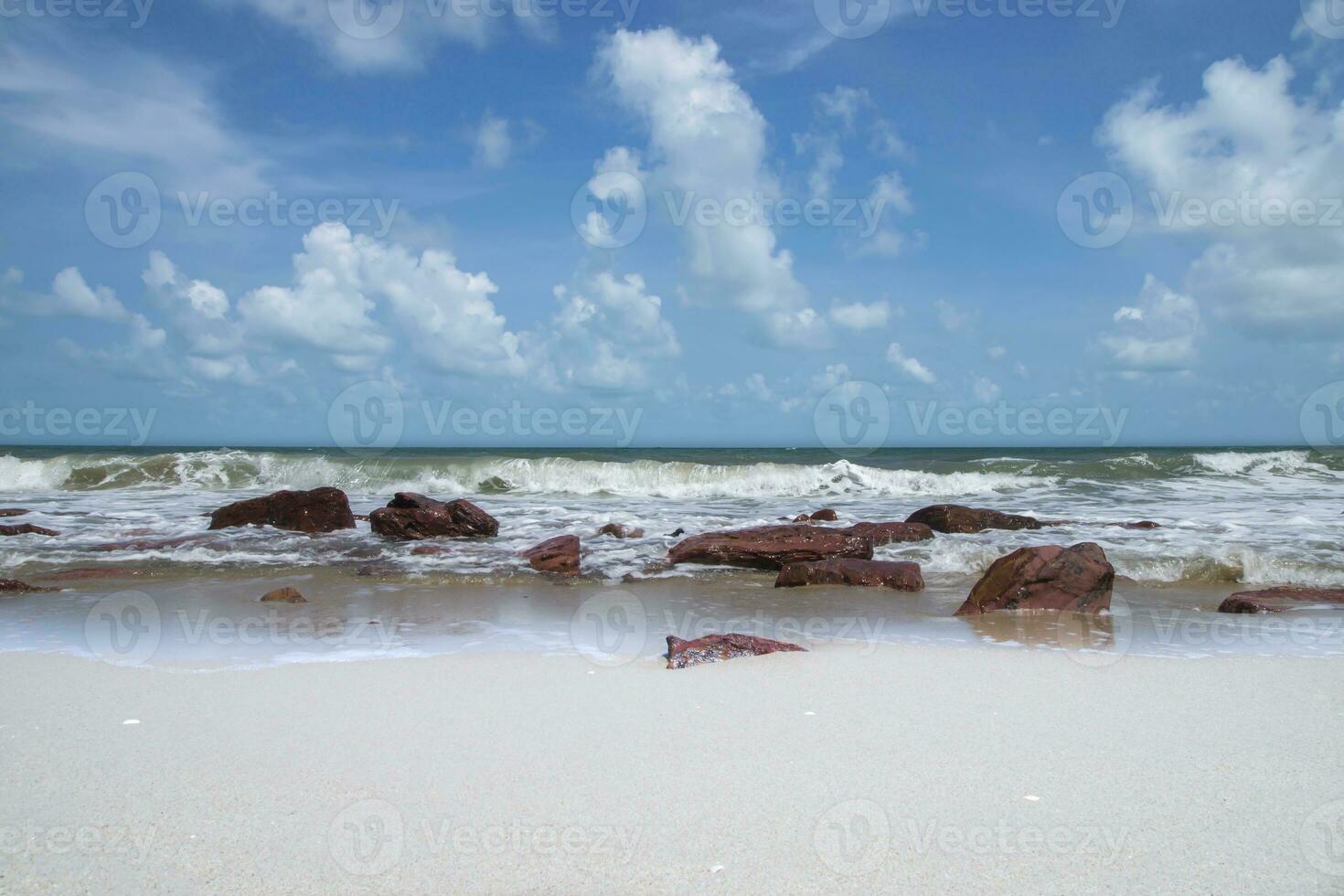 ondas e vento dentro a verão com vermelho Rocha em a de praia. foto