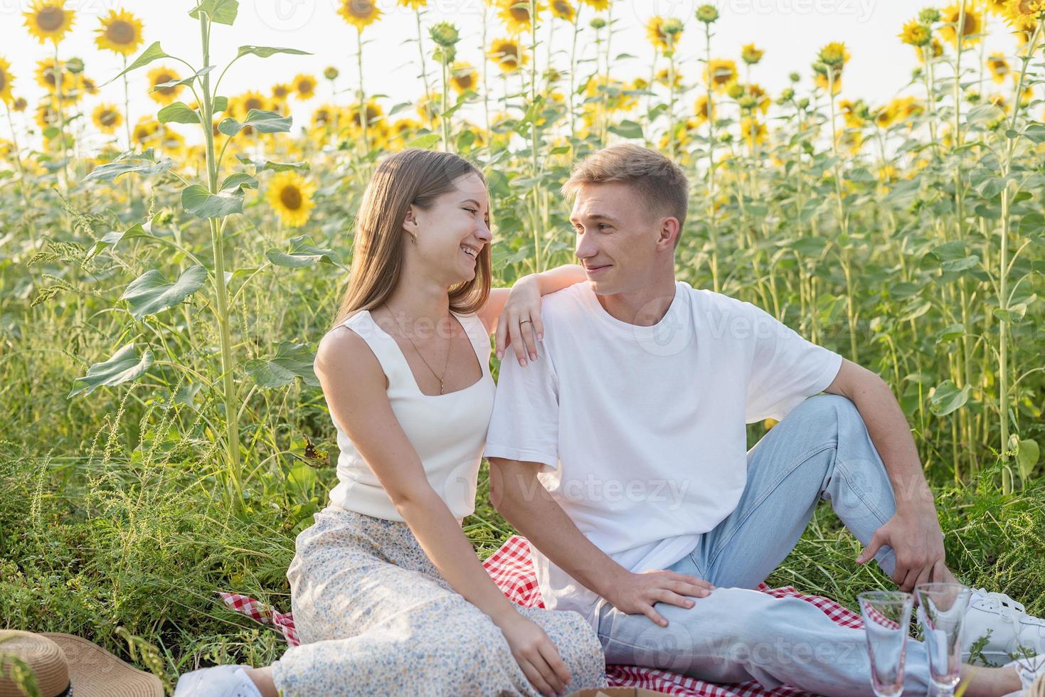 jovem casal fazendo piquenique no campo de girassol foto