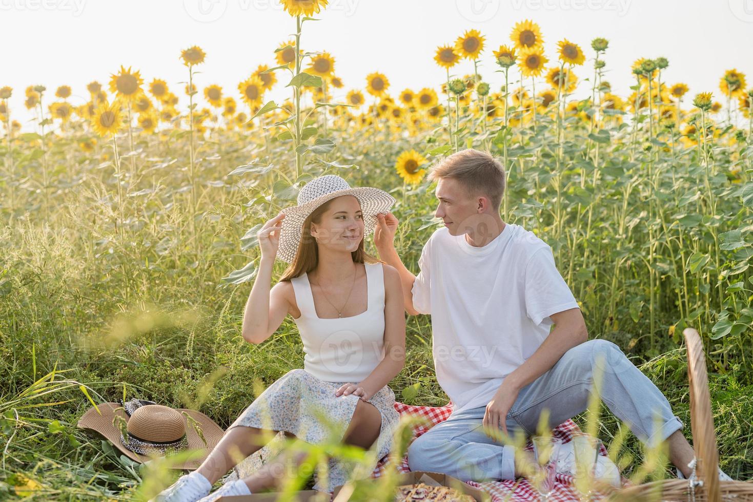 jovem casal fazendo piquenique no campo de girassol foto