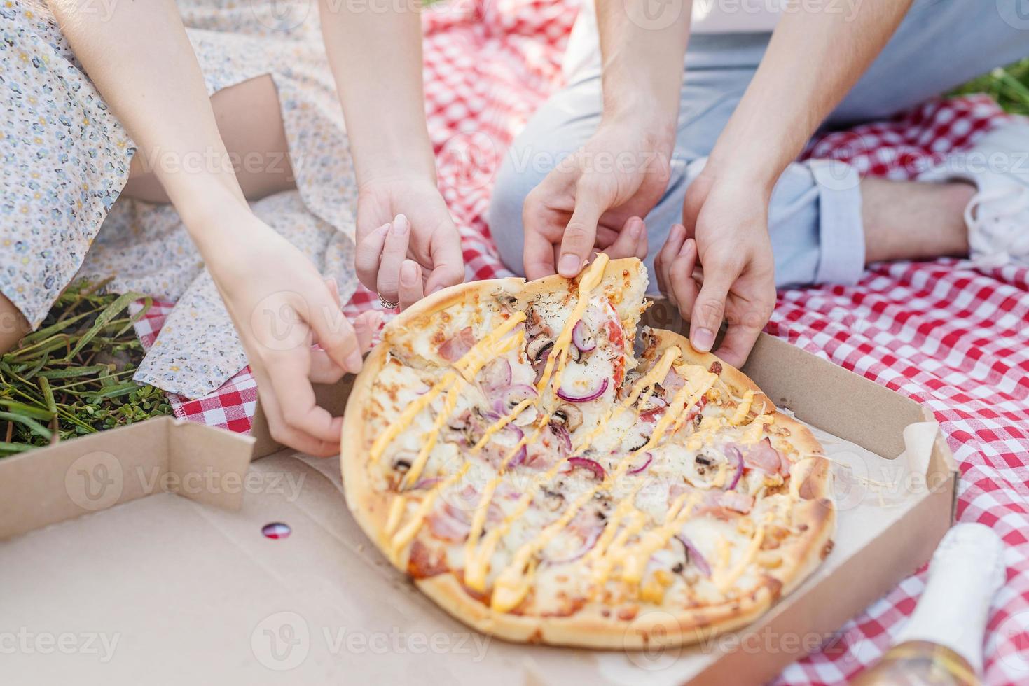 jovem casal fazendo piquenique comendo pizza foto