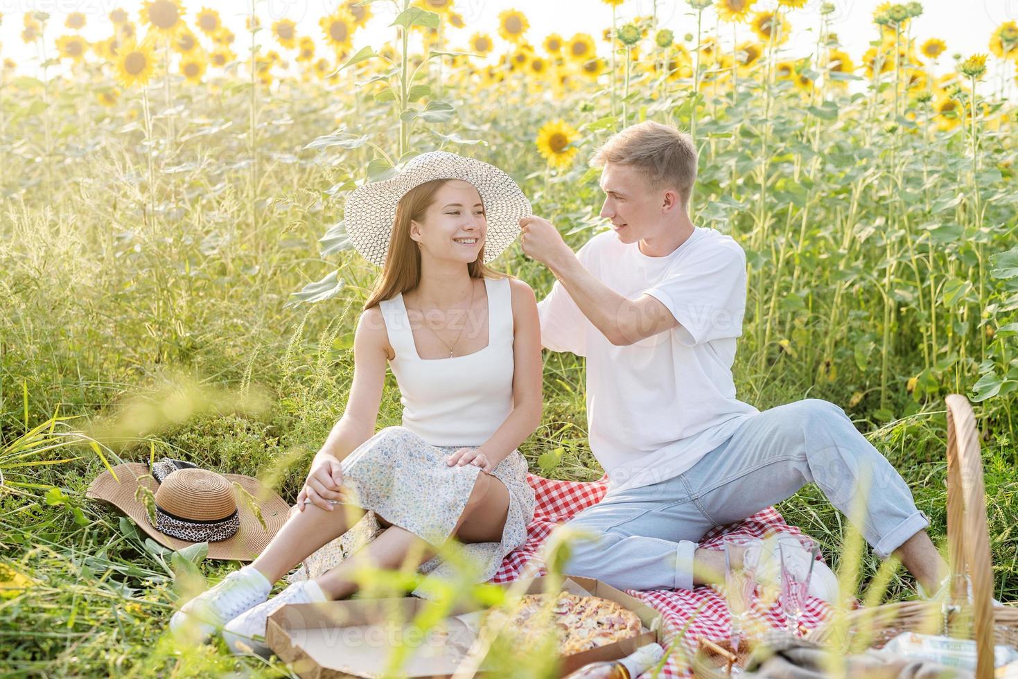 jovem casal fazendo piquenique no campo de girassol foto